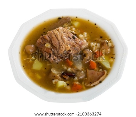 Appetizing pork and mushroom soup with vegetables and pearl barley. Comfort food. Isolated over white background.