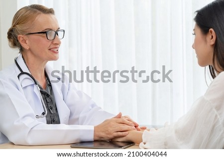 Caucasian woman doctor consulting to patient and hold her hand to encourage.