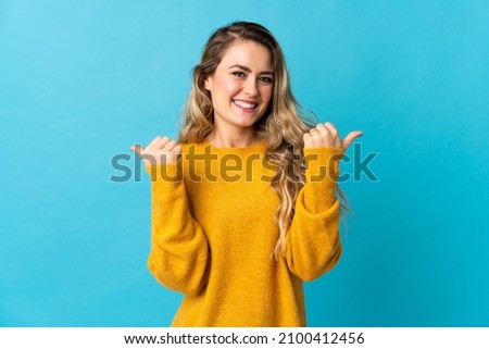 Young Brazilian woman isolated on blue background with thumbs up gesture and smiling