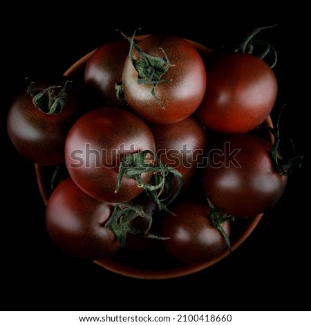 Ripe juicy tomatoes on a black background. Cumato tomatoes. a top view.