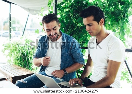 Male freelancers discussing web project and graphic design while creating web page on modern laptop technology, skilled remote colleagues using netbook application for networking in social media