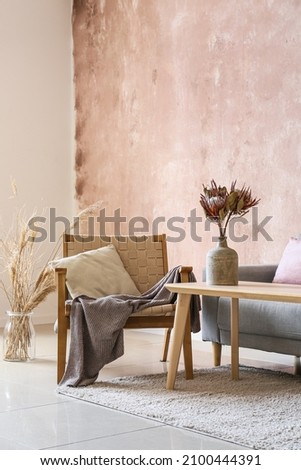 Modern armchair, sofa and table with vase near color wall