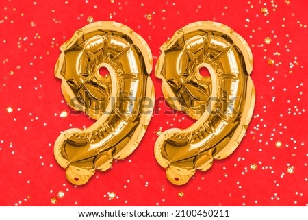 The number of the balloon made of golden foil, the number ninety-nine on a red background with sequins. Birthday greeting card with inscription 99. Numerical digit, Celebration event, template.