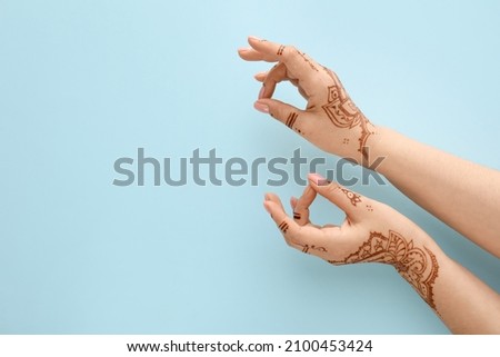 Beautiful female hands with henna tattoo on blue background Royalty-Free Stock Photo #2100453424