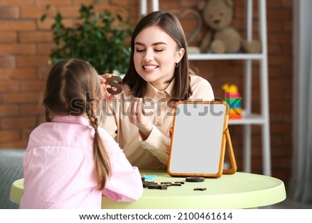 Speech therapist working with cute girl in clinic Royalty-Free Stock Photo #2100461614