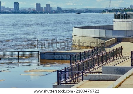 Descent to the Amur River from the granite embankment of Blagoveshchensk, Russia during a flood. View of Heihe city, China. Summer day.