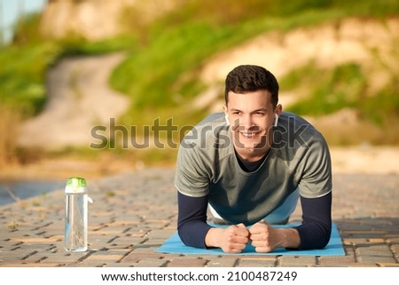 Sporty young man doing plank outdoors