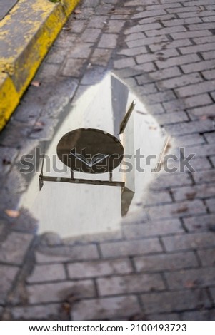 An shop sign mirror in the water puddle in the street.