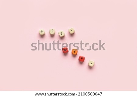 Little wooden cubes with word WiFi on pink background