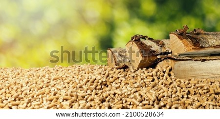 biomass - wood pellets and birch firewood on green leaf background. renewable energy