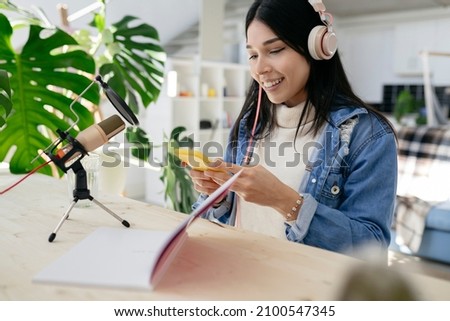 pretty latin hispanic woman doing a podcast with microphone notebook smartphone at home