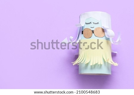 Figure of cute doll made of cardboard tube for toilet paper on color background