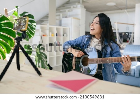 Vloger looking at camera lens while recording playing guitar, Influence of new media stars on social media talking about video equipment for shows