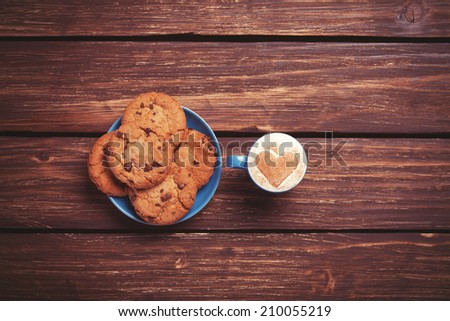 Cookie and cup of coffee on wooden table. Photo in retro color image style.