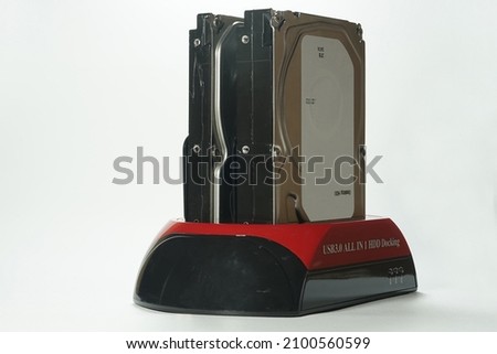 USB 3.0 HDD docking station is an adapter for reading 2.5 inch or 3.5 inch hard drives via USB cable. Red and black HDD docking made of plastic on white background isolated. Royalty-Free Stock Photo #2100560599