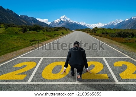 The 2022 New Year journey and future vision concept . Businessman traveling on highway road leading forward to happy new year celebration in beginning of 2021 for fresh and successful start . Royalty-Free Stock Photo #2100565855