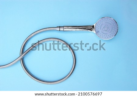 The shower head chrome coated multi-mode for the bathroom with hose on blue background. Top view Royalty-Free Stock Photo #2100576697