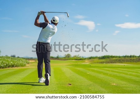 Asian man golfing on the course in summer Royalty-Free Stock Photo #2100584755