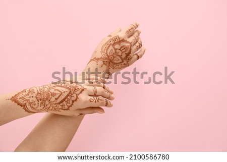 Beautiful female hands with henna tattoo  on pink background