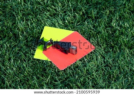 Referee soccer, football game whistle, red and yellow cards on green grass. Two penalty cards and a whistle for the referee  F
