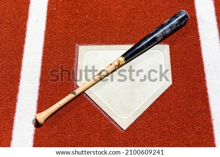 A high angle shot of a baseball and a bat on the ground