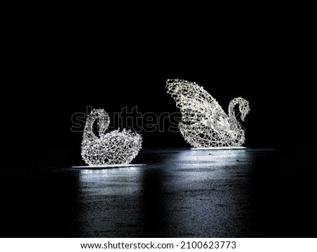 Shining statues of swans on the surface of the pond

