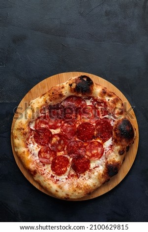 Tasty pepperoni pizza and cooking ingredients tomatoes basil on black concrete background. Top view of hot pepperoni pizza. With copy space for text. Flat lay.