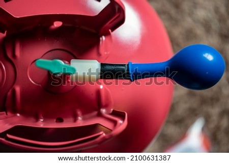 Selective focus on edge of an inflatable balloon attached to a helium canister. Royalty-Free Stock Photo #2100631387