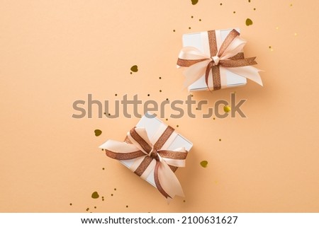 Top view photo of saint valentine's day decorations white gift boxes with glowing brown and light beige ribbon bows golden heart shaped confetti sequins on isolated beige background with copyspace