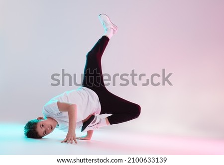 Modern dances style. Cool breakdancer boy dancing in studio on a white background in mixed colored lighting. Hip-hop dancer. Sports and activities.