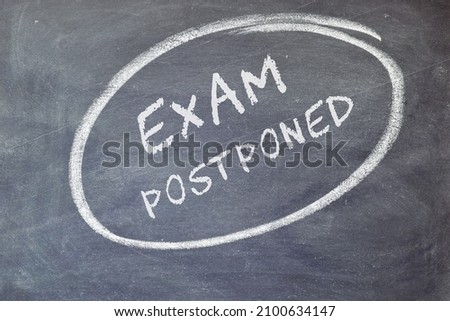 EXAM postponed text on blackboard background.  Royalty-Free Stock Photo #2100634147