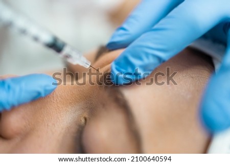 Close up of botox injection in the eyebrow or forehead of female patient Royalty-Free Stock Photo #2100640594