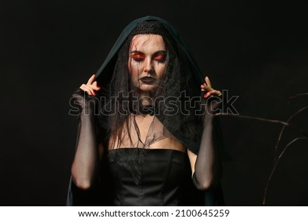 Beautiful woman dressed as witch for Halloween on dark background