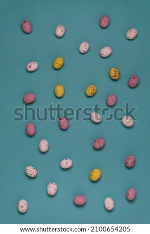 Lots of colored eggs  on a blue background. Yellow, white and pink chocolate eggs for Easter celebration.
