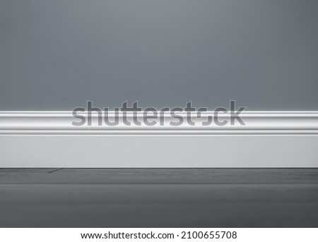 Close up of decorative, moulding white baseboard in empty room with copy space Royalty-Free Stock Photo #2100655708