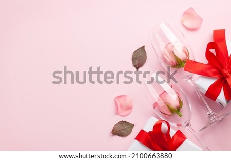 Champagne glasses, gift box and rose flower petals. Valentines day greeting card with space for your greetings. Top view flat lay