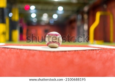 A selective focus shot of a softball on the mat on red ground