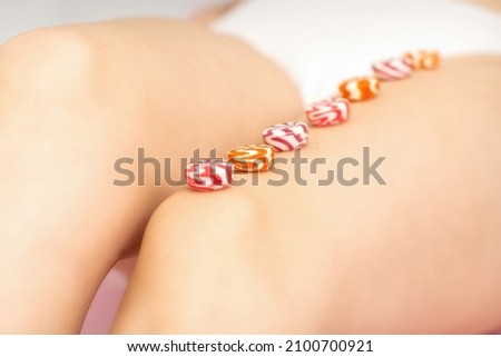 Round candies lying in a row on the female leg with copy space, depilation concept.