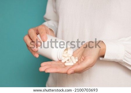 close-up of a woman pouring capsules from a jar into her hand