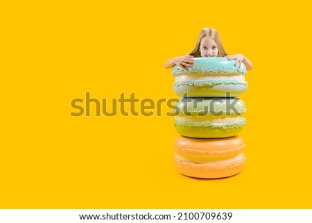Sweet gift. Round dessert. A cute girl stands behind macaroons, holding them with her hands. Christmas sweetness.