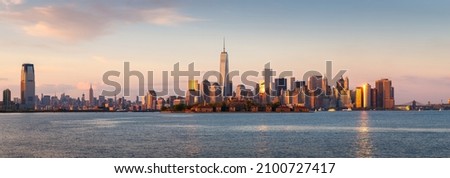 New York City Lower Manhattan skycrapers panoramic view at sunset. Ellis Island in New York Harbor with the World Trade Center