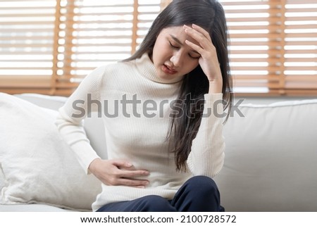 Flatulence asian young woman, girl hand in stomach ache, suffer from food poisoning, abdominal pain and colon problem, gastritis or diarrhoea. Patient belly, abdomen or inflammation, concept. Royalty-Free Stock Photo #2100728572