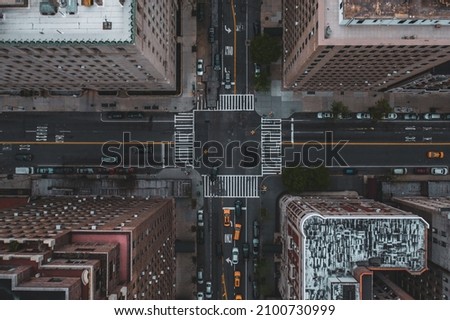 A bird's eye view of the traffic at the crossroad surrounded by skyscrapers Royalty-Free Stock Photo #2100730999