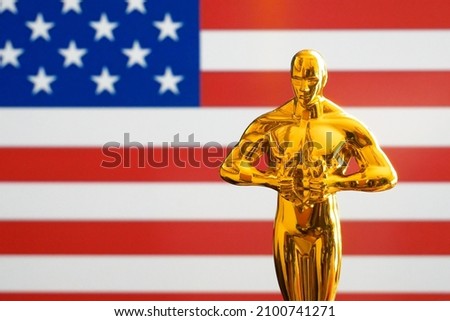 Hollywood Golden Oscar Academy award statue on american flag usa background. Success and victory concept.