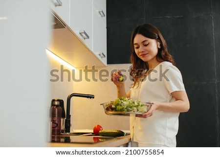 Young woman preparing salad in kitchen, stock photo
