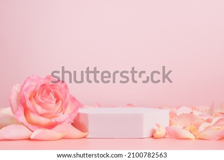Empty podium with pink rose flowers on pink background to display products, gift or cosmetics. Podium with copy space for design or advertising