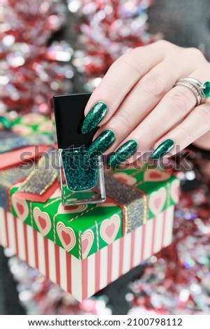 Women's hands with long nails and bright green manicure. Congratulations to the New Year and Christmas.