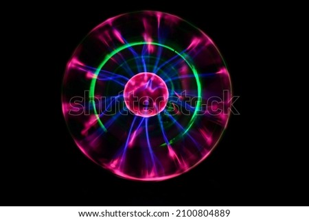 Plasma ball with iridescent lightning in different colors on a very dark background