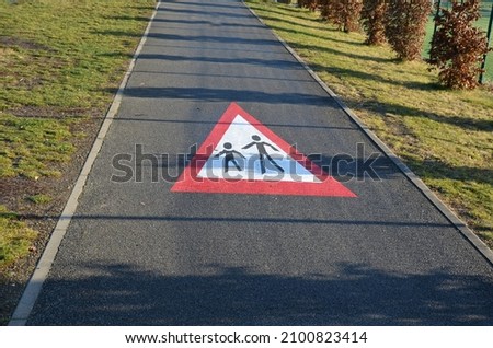 pedestrian crossing sign, pedestrian zone, beware of pedestrians on the road. horizontal signage on asphalt red triangle with a symbol of people children in latex color on a bike path.