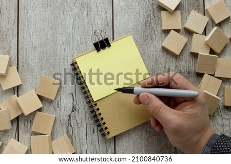 Business concept - top view of notepad and sticker on wood table near wood blocks. Top view flat lay with copy space